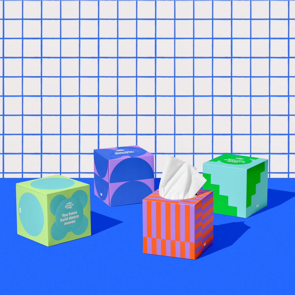 Four boxes of of Who Gives a Crap recycled tissues against blue and white bathroom wall