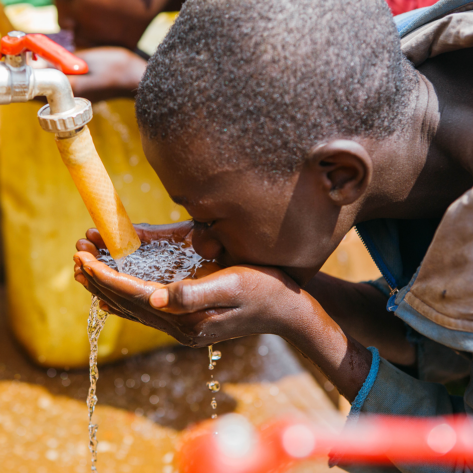 Close-up of a boy drinking from his cupped hands under a running tap in Rwanda